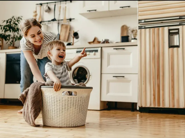 woman playing with child while laundry machine does the wash